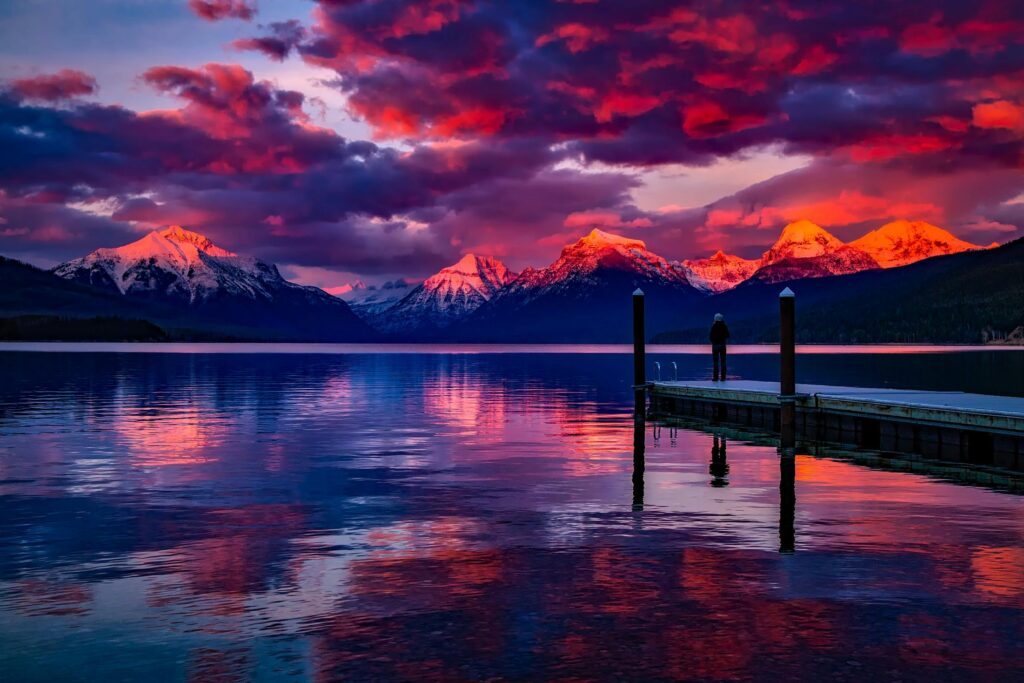 Stunning sunset over a serene lake with colorful sky and majestic mountains.