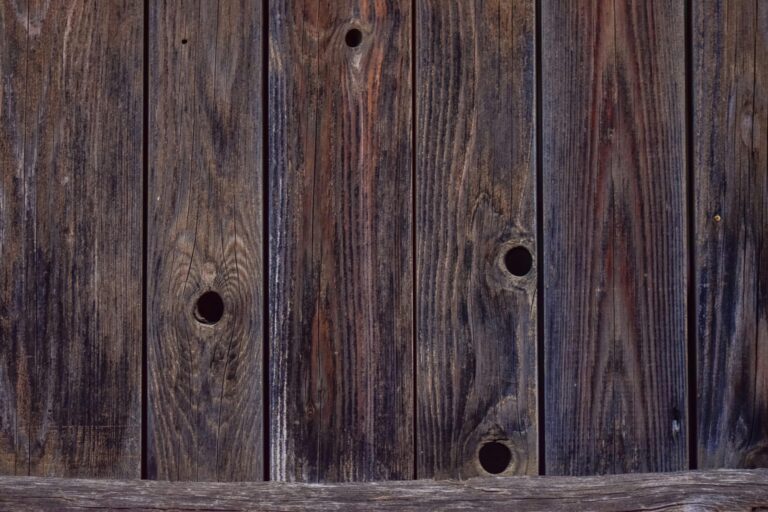 Close-up of weathered wooden planks with holes, ideal for rustic backgrounds.