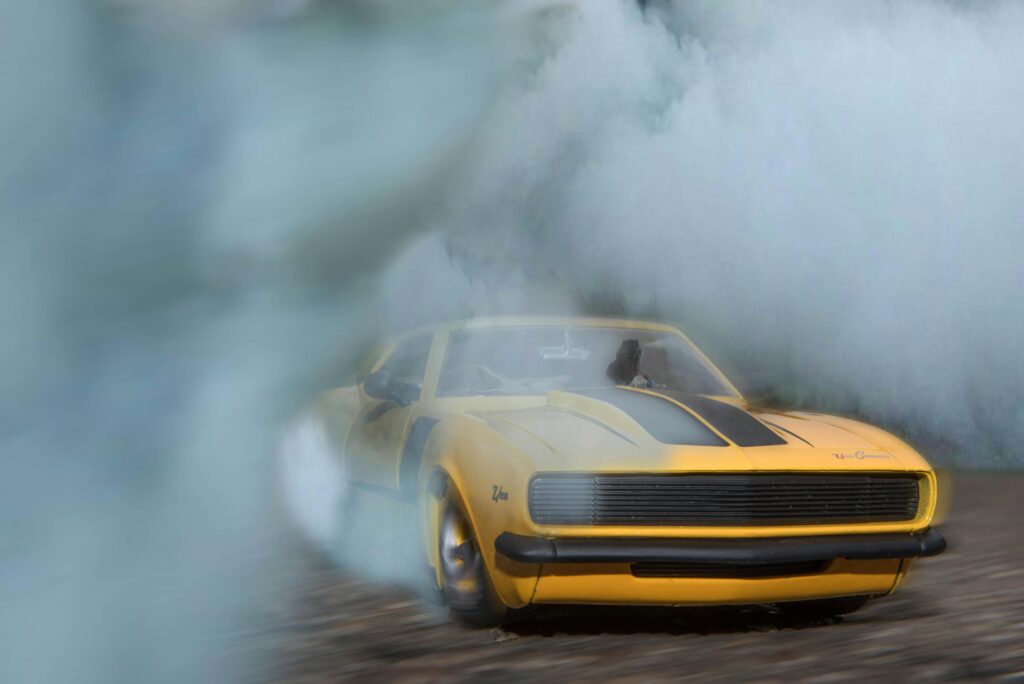 1969 Camaro drifting on pavement with smoke engulfing the car, showcasing its power.