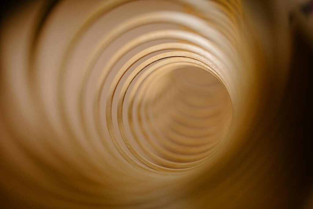 Abstract view of concentric circles forming a tunnel-like vortex in warm tones.