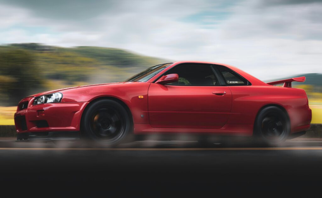 Vibrant red sports car speeds along a scenic highway, showcasing sleek design and performance.