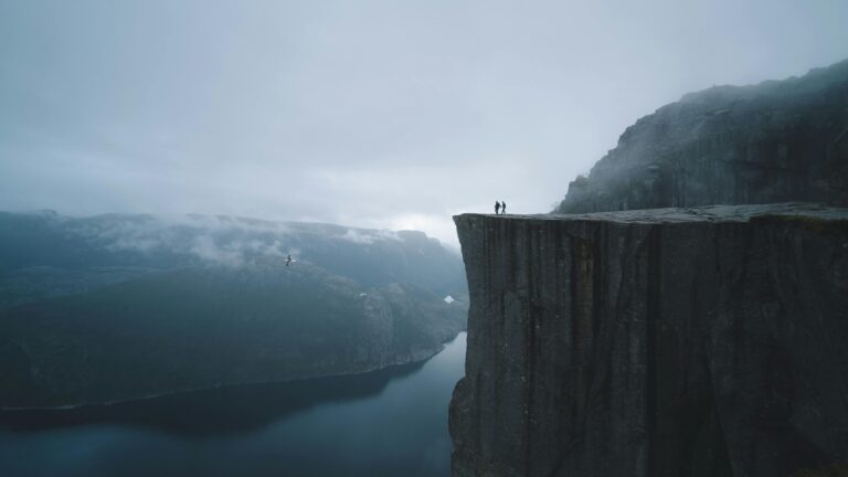 Dramatic view of Preikestolen cliff in Norway with mist and fjord.