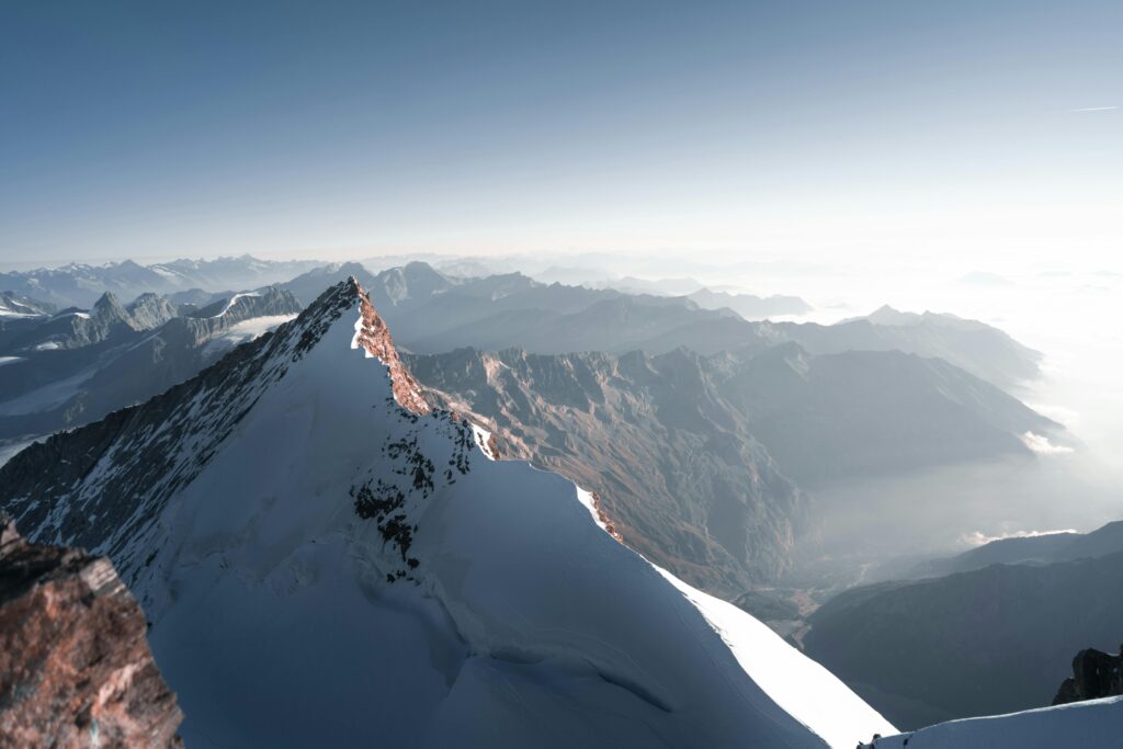 Breathtaking view of a snow-covered mountain peak with a vast landscape at sunrise, highlighting natural beauty.